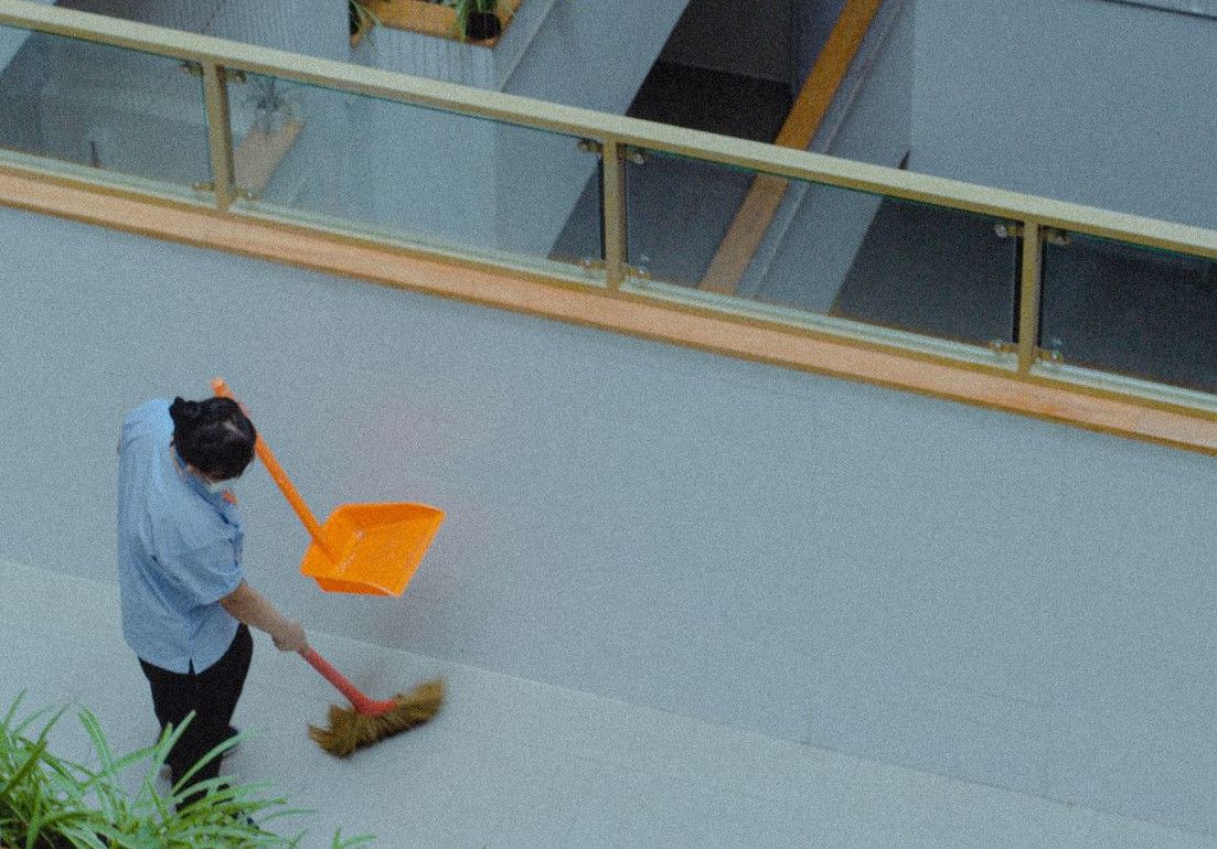 A man with a broom is sweeping the street