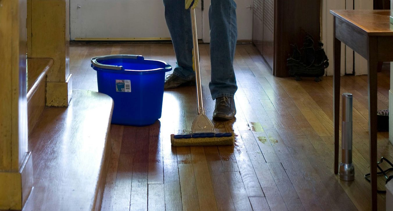 man in gray hoodie and blue denim jeans standing on brown wooden parquet flooring