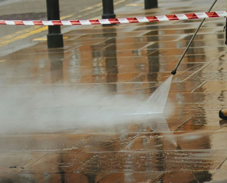 a man in a yellow jacket is using a pressure washer
